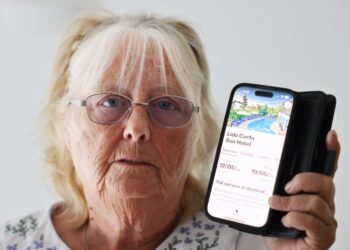 Mujer sosteniendo teléfono que muestra una reserva de hotel Tui.