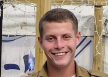 Retrato de un joven sonriente con un uniforme militar.
