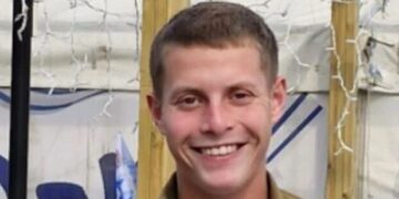 Retrato de un joven sonriente con un uniforme militar.