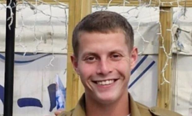 Retrato de un joven sonriente con un uniforme militar.