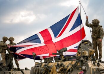 Soldados colocando una bandera británica en un vehículo militar.