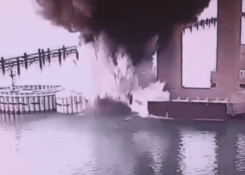 Gran fuego y humo cerca de un cuerpo de agua.