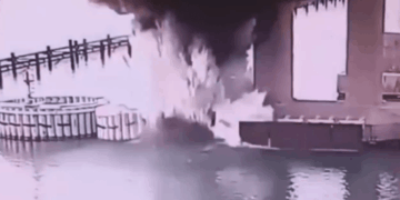 Gran fuego y humo cerca de un cuerpo de agua.