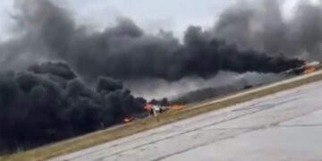 Gran columna de humo negro que se eleva desde un aeródromo en llamas.