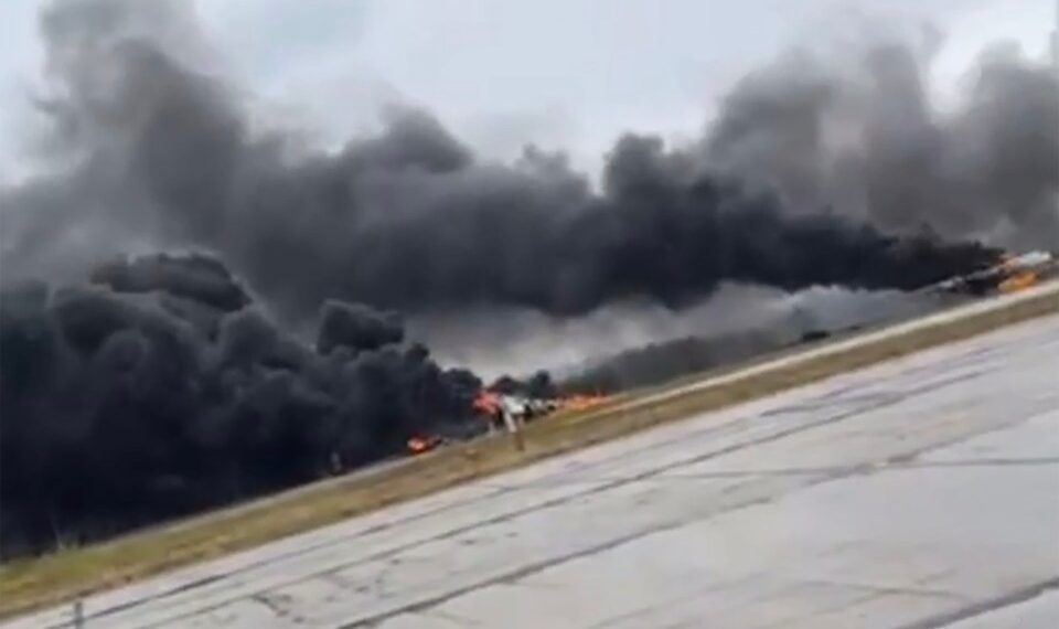 Gran columna de humo negro que se eleva desde un aeródromo en llamas.