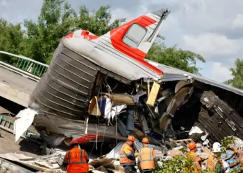Los especialistas en servicios de emergencia se reúnen cerca de un carruaje destruido en la escena, después de que un puente de carretera se derrumbó en vías del ferrocarril que descarrilaba un tren que se acercaba en la región de Bryansk, Rusia, el 1 de junio de 2025. (Stringer/Reuters)
