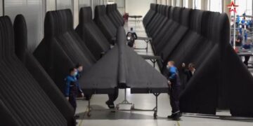 Persona que inspecciona un ala de avión grande de color oscuro.