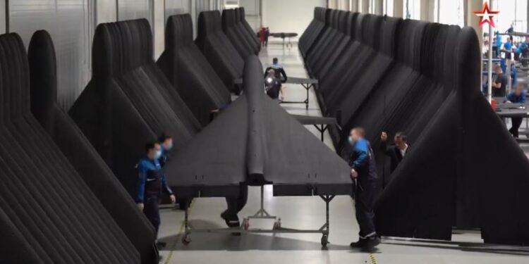 Persona que inspecciona un ala de avión grande de color oscuro.