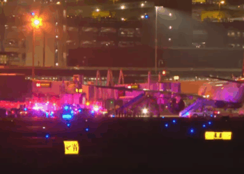 Vehículos de emergencia que rodean un avión en una pista de aeropuerto por la noche.