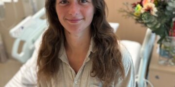 Mujer en la cama del hospital con oso de peluche.