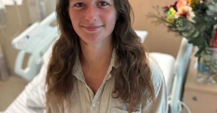 Mujer en la cama del hospital con oso de peluche.