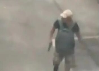 Imágenes de vigilancia de un hombre que lleva un arma en un estacionamiento.