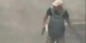 Imágenes de vigilancia de un hombre que lleva un arma en un estacionamiento.