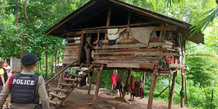 Oficiales de policía en una casa de madera en ruinas en una zona boscosa.