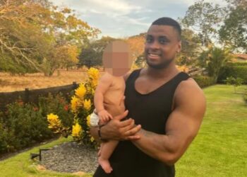 Hombre sosteniendo a un bebé al aire libre.