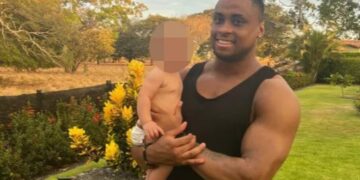 Hombre sosteniendo a un bebé al aire libre.