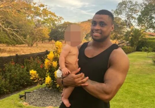 Hombre sosteniendo a un bebé al aire libre.