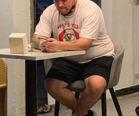 Hombre sentado en una mesa mirando su teléfono.