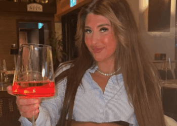 Mujer sosteniendo un vaso de Aperol Spritz en un restaurante.