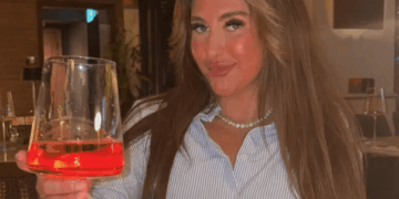 Mujer sosteniendo un vaso de Aperol Spritz en un restaurante.