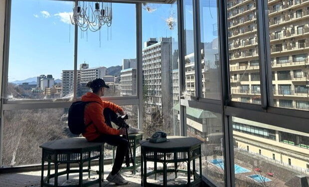 Persona filmando un hotel japonés abandonado con vistas a otros edificios.