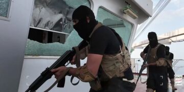 Hombres armados con equipo táctico negro a bordo de un barco.