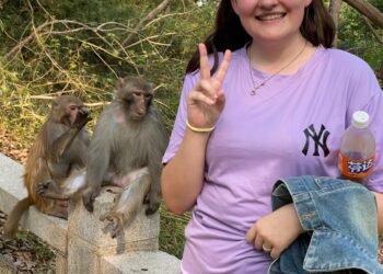 La mujer hace un signo de paz con monos detrás de ella.