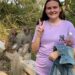La mujer hace un signo de paz con monos detrás de ella.