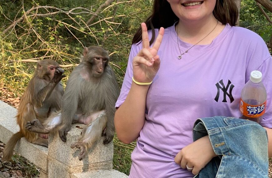 La mujer hace un signo de paz con monos detrás de ella.