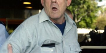 Un oficial de policía que lleva a un sospechoso lejos de la Corte Suprema de Adelaide.