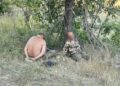 Dos hombres atados sentados debajo de un árbol.