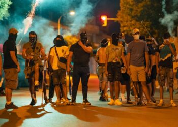 Los manifestantes que usan caras y transportando armas durante un motín.