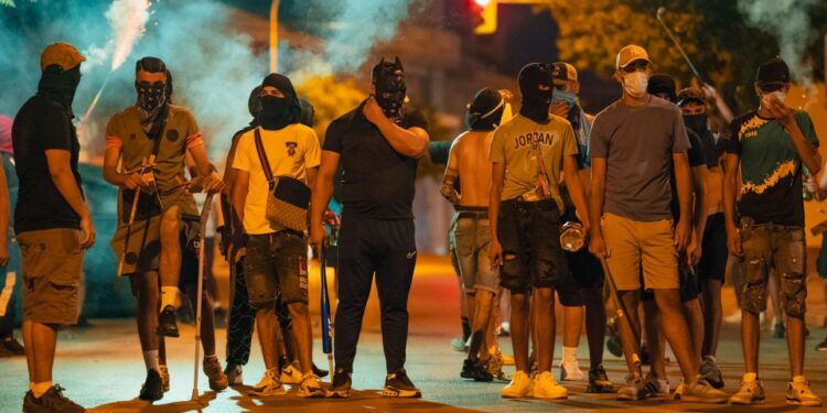 Los manifestantes que usan caras y transportando armas durante un motín.