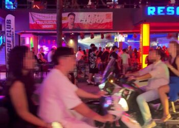 Gente en motocicletas afuera de un club nocturno.