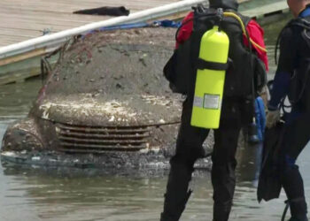 Auto cubierto de barro de agua; buzos cerca.