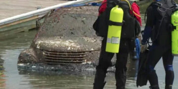 Auto cubierto de barro de agua; buzos cerca.