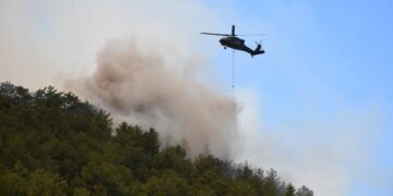 Helicóptero que cae agua sobre un incendio forestal.