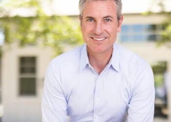 Retrato de un hombre sonriente con una camisa azul claro.
