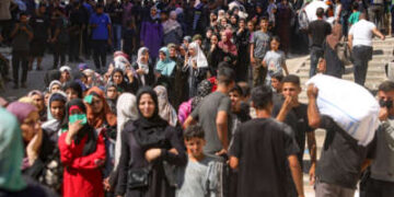 Los palestinos llevan bolsas de harina mientras otros esperan frente a un punto de distribución establecido por la Sociedad Independent Save Youth Future Future, en coordinación con el Programa de Alimentos Mundiales de la ONU, en la ciudad de Gaza el 26 de junio de 2025.