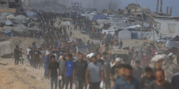 Los palestinos que llevan ayuda a través de un área dañada.