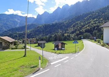 Sacron Mis, Italia: un camino se curva a través de un pueblo ubicado en un valle de montaña.