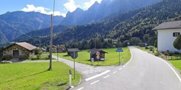 Sacron Mis, Italia: un camino se curva a través de un pueblo ubicado en un valle de montaña.