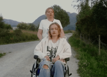 Mujer empujando a una mujer joven en una silla de ruedas por un camino rural.