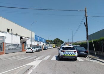 Escena callejera de autos estacionados cerca de un vehículo policial.