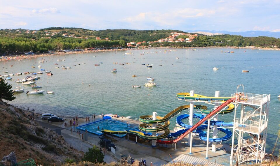 Vista aérea de una playa con toboganes de agua y muchos barcos.