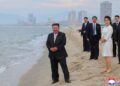 Kim Jong Un y su hija en una playa con una ciudad en el fondo.