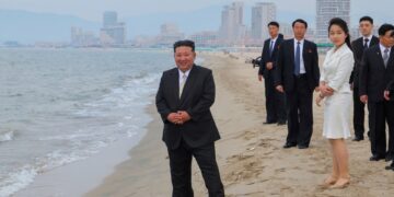 Kim Jong Un y su hija en una playa con una ciudad en el fondo.