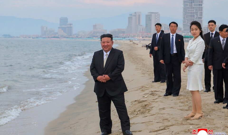 Kim Jong Un y su hija en una playa con una ciudad en el fondo.