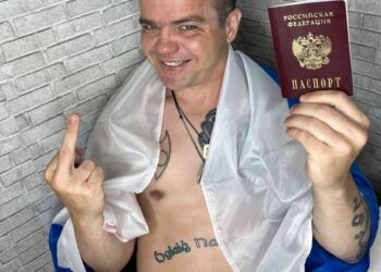 Hombre sosteniendo pasaporte ruso y dando el dedo medio.