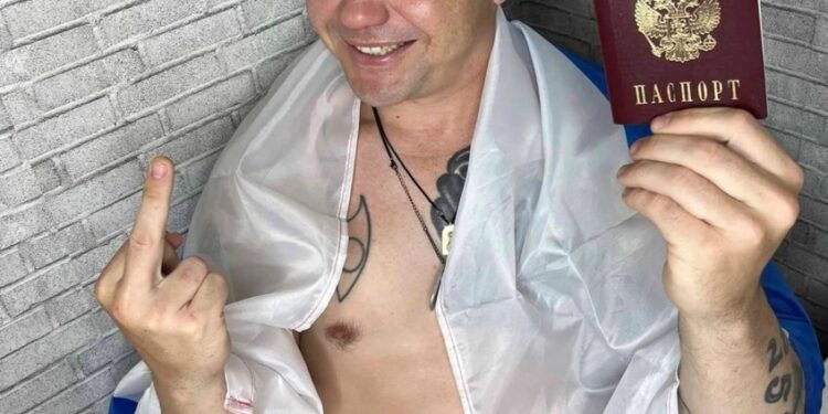 Hombre sosteniendo pasaporte ruso y dando el dedo medio.